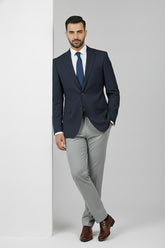 Man wearing navy slim fit two-button suit with light grey trousers and brown shoes.